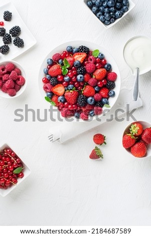 Bowl of healthy fresh berry fruit meal with cream on white background. Top view. Berries overhead closeup colorful assorted mix of strawberry, blueberry, raspberry, blackberry, red currant Royalty-Free Stock Photo #2184687589