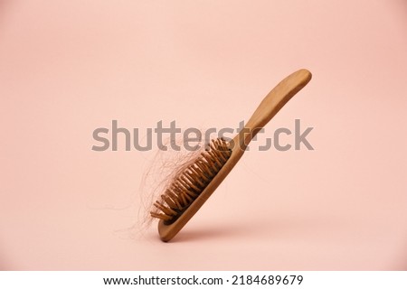 wooden hair brush with lost hair on the pink background Royalty-Free Stock Photo #2184689679