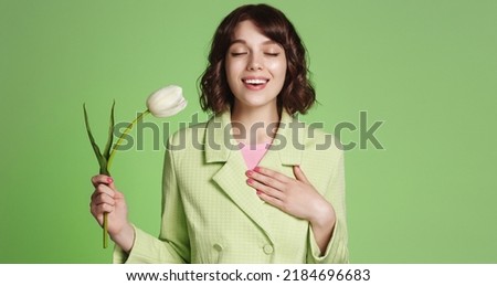 Smiling woman feeling relieved and happy, holds white tulip. Girl with flower inhale air with joyful face, no allergy Royalty-Free Stock Photo #2184696683