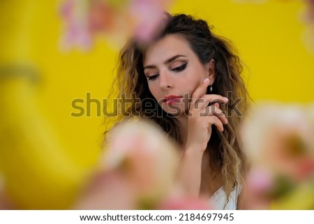 Close-up portrait of a beautiful girl on a yellow background. woman posing on a background of colorful flowers.