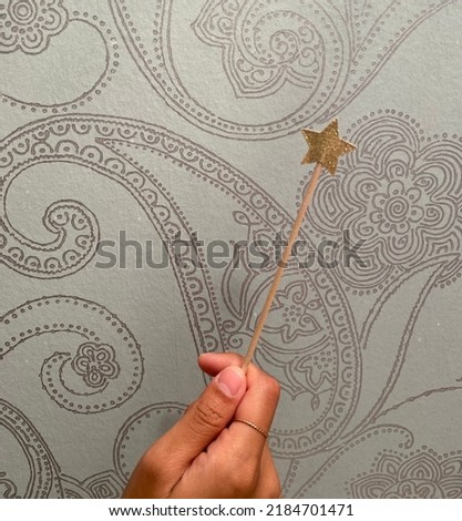 When you wish upon a star. A woman holds a stick against a henna background