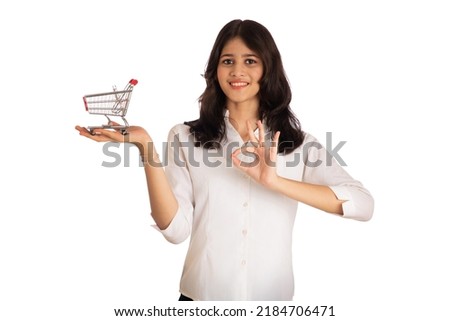 Happy young Smiling girl with a miniature trolley shopping cart on a white background. Beautiful girl in shopping concept.