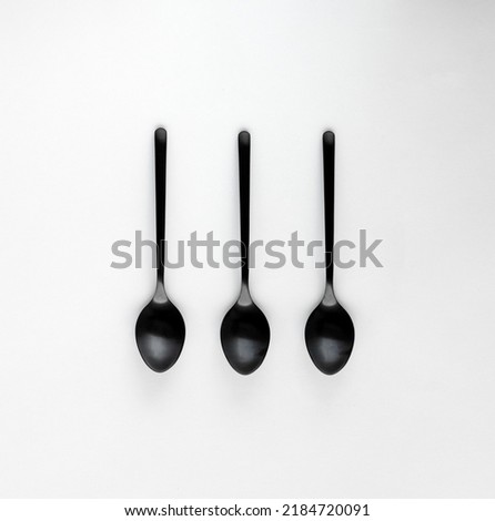 A set of black teaspoons isolated on a white background. Top view. Center composition. Minimalism concept.