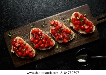 Bruschetta on sour dough bread with a moody vibe. Bright red tomatoes. Flat lay photography. Horizontal, high resolution. 