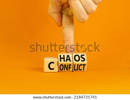 From conflict to chaos symbol. Concept words Conflict and Chaos on wooden cubes. Businessman hand. Beautiful orange background. Businessman hand. Business Conflict and Chaos concept. Copy space.