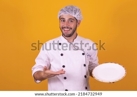 cooking, culinary and people concept - happy smiling male chef in Toque holding empty plate yellow gray background