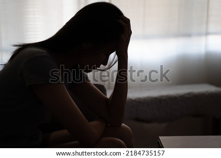 Depressed woman sitting alone on the bed with hands on head feel stress, sad and worried in the dark bedroom and low light environment Royalty-Free Stock Photo #2184735157