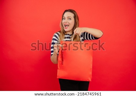 Delightful satisfied and proud shouted woman with red shopper bag and pepper on red background. Enjoy summer shopping and big hot amazed sales, buying clothes and accessories. Black Friday, copy