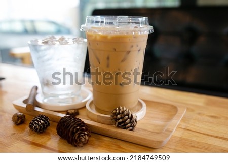 Glass of cool water and cool coffee on wooden table in coffee shop background.