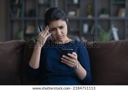 Unhappy young Indian woman distressed with payment problems shopping online from home on smartphone with credit debit card. Upset biracial female buyer frustrated with bank error on cell. Royalty-Free Stock Photo #2184751113