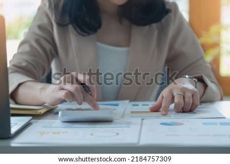 Closeup Portrait of a female accountant using a calculator and laptop to calculate balance using graphs for customers.