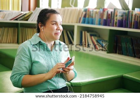 Portrait of Asian woman with blindness disability enjoy using smart phone with voice accessibility for persons with visual impairment in creative workplace library. Royalty-Free Stock Photo #2184758945