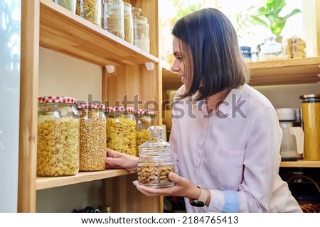 Young woman in kitchen with containers jars of food