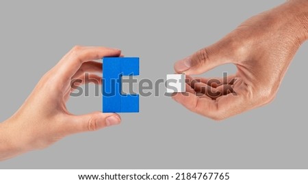 Man and woman hands joining two puzzle pieces. Partnership, connection concept. Partners suitable for each other. High quality photo