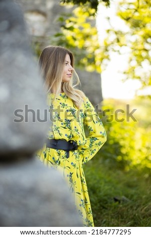 A tall girl in a colorful dress near the castle wall