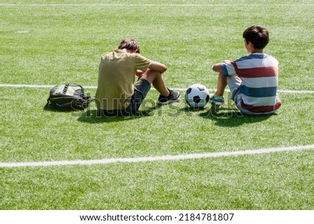 Children talking in school stadium outdoors. Teenage boy comforting consoling upset sad friend. Education, bullying, conflict, social relations, problems at school, learning difficulties concept Royalty-Free Stock Photo #2184781807