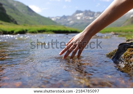 Clos eup of a woman wand touching river water in the mountain Royalty-Free Stock Photo #2184785097