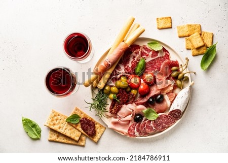 Appetizers with differents antipasti, charcuterie, snacks and red wine on white background. Sausage, ham, tapas, olives and crackers for buffet party. Top view, flat lay Royalty-Free Stock Photo #2184786911