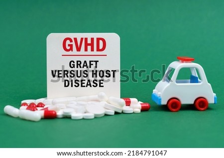 Medical concept. On a green surface, an ambulance, pills and a white sign with the inscription - Graft Versus Host Disease