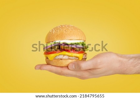 hamburger in hand on yellow isolated background