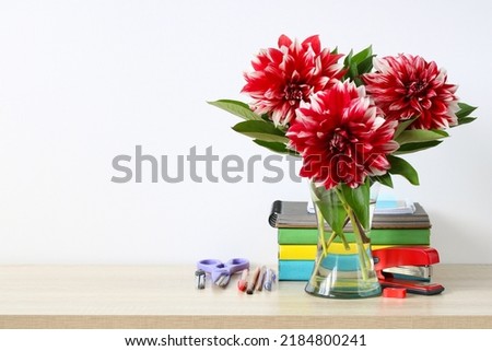 A bouquet of red dahlias and school supplies. Back to school background.