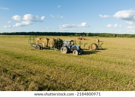 Hay Making in autumn season. Farmer loading round bales of straw from Hay Trailer with a front end loader. Store hay at farm. Hay rolls as Forage feed for livestock. Royalty-Free Stock Photo #2184800971