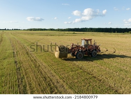 Hay Making in autumn season. Farmer loading round bales of straw from Hay Trailer with a front end loader. Store hay at farm. Hay rolls as Forage feed for livestock. Royalty-Free Stock Photo #2184800979