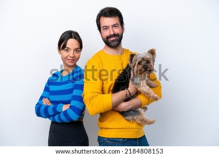 Young hispanic woman holding a dog isolated on white background keeping arms crossed