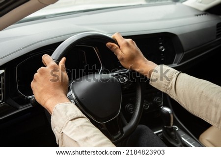 Two hands hold the steering wheel inside the car. Royalty-Free Stock Photo #2184823903