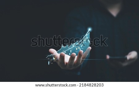 Businessman hand holding virtual stock market graph chart for trader technical analysis business investment concept. Royalty-Free Stock Photo #2184828203