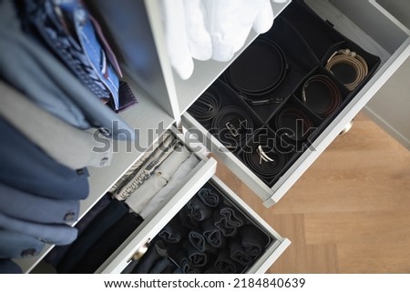 Man cupboard clothes storage organization with open dresser drawer neatly folded belt underwear shirt and socks top view. Male wardrobe hanging clean fashion clothes coat blazer garment attire keeping Royalty-Free Stock Photo #2184840639