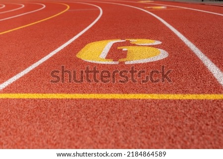 Close up lane number six, 6, on a new red running track with white lane lines and other markings.	 Royalty-Free Stock Photo #2184864589