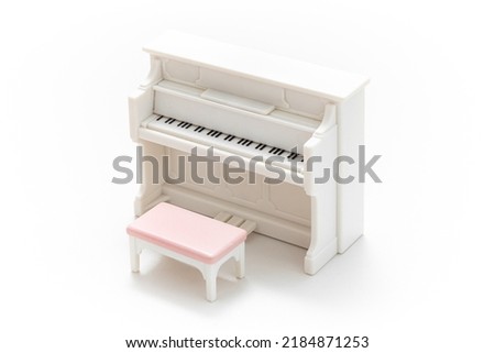 Miniature piano isolated on white background. Miniature dollhouse furniture. Kids toy. Play and learn. Kids room. Childhood. Kindergarten toy. Developmental toys. Plastic toy.