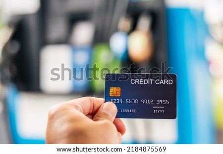 closeup of blue credit card holded by hand on gas station blurred background,copy space for text.