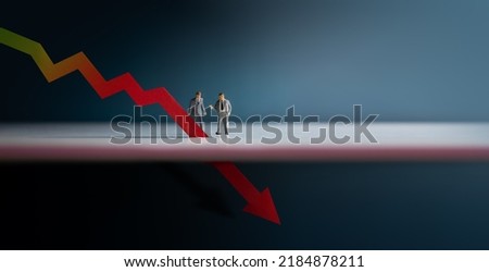 Recession, Inflation and Depression Concepts. Economic Crisis. Graph Fall Down, Business Collapse. Two Miniature Figure of Businessman Looking at a Red Graph Arrow Down Royalty-Free Stock Photo #2184878211