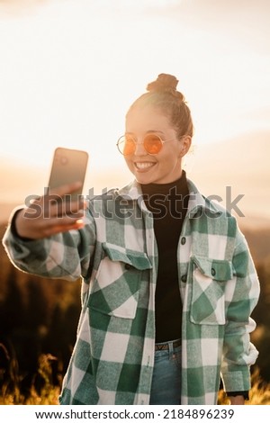 Fashion woman having fun taking self portrait on sunset during evening sunset with orange light. 