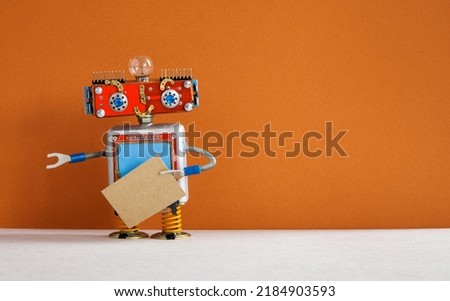 Robot with a cardboard mockup. Creative design robotic toy holding a blank empty paper poster, brown wall background. copy space for text and design elements.