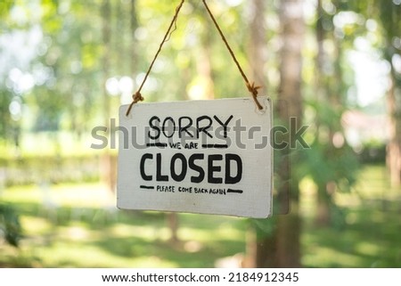 "Sorry, we are closed" wooden banner of cafe or restaurant, with background of outdoor environment. Sign and symbol object photo.