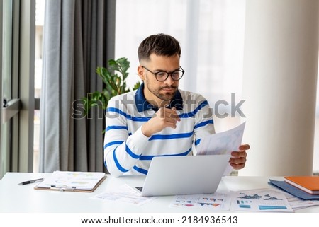 Business professionals. Business man analyzing data using computer while spending time in the office. Young grinning professional man in office. Graphs and charts