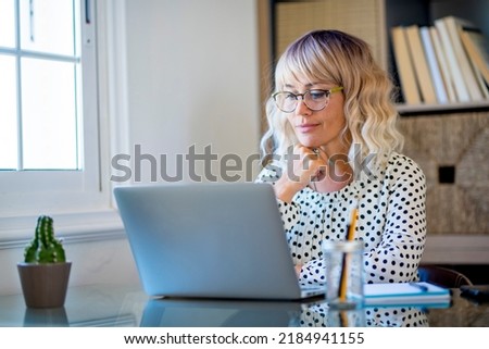 Modern freelance entrepreneur woman working on a laptop in home studio workplace. Happy female smiling in front of computer doing a video call conference. Job online people business on web internet Royalty-Free Stock Photo #2184941155