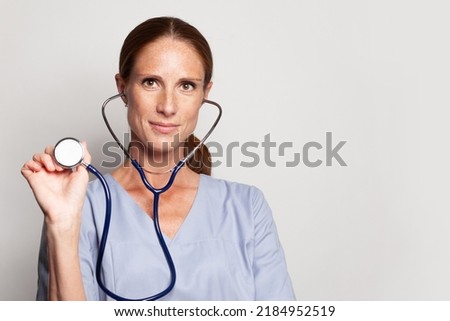 Head shot of woman professiona medical worker wearing blue medical coat holding stethoscope, portrait