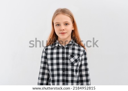Portrait of teen girl with fair-haired looking at camera, standing in casual shirt. Indoor studio shot on white background