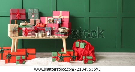 Wooden bench with Christmas gifts and Santa bag near green wall in room