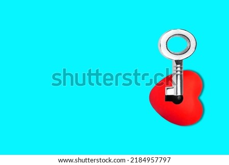 Heart with a keyhole and a skeleton key isolated on blue background. Creative relationships concept.