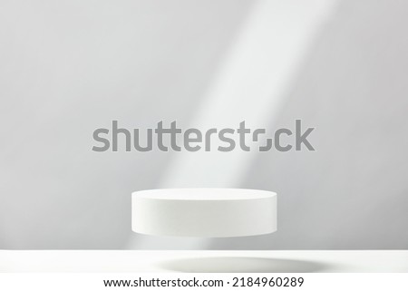 Abstract empty white podium with geometric shadows on blue background. Mock up stand for product presentation. 3D Render. Minimal concept. Advertising template Royalty-Free Stock Photo #2184960289