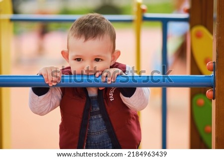 Sad toddler baby boy on the playground, unhappy child aged one year