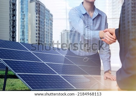 Double exposure of businesspeople shaking hands and solar panels installed outdoors. Alternative energy source Royalty-Free Stock Photo #2184968113