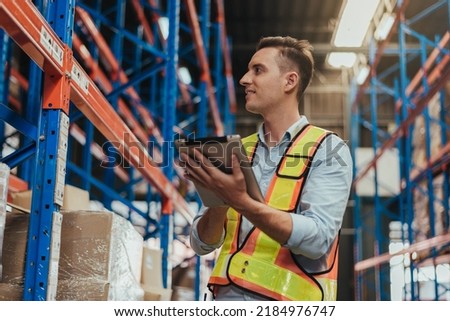 Warehouse Workers Checking Stock with digital Tablet in Logistic center. Caucasian manager wearing safety vests to working about shipment in storehouse, Working in Storage Distribution Center. Royalty-Free Stock Photo #2184976747