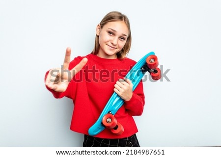 Young skater caucasian girl isolated on blue background