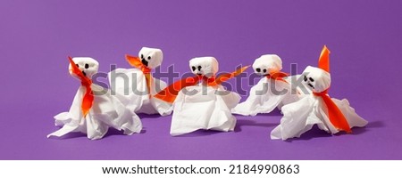 Halloween paper decorations on bright purple violet background. Black  ghosts from paper napkins. Halloween concept. Flat lay, top view, overhead. Party greeting card, invitation, flyer, banner